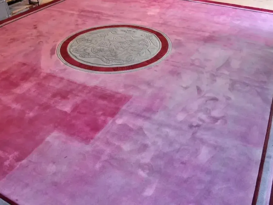 Patterned rug with uneven colour loss across its central field before professional restoration