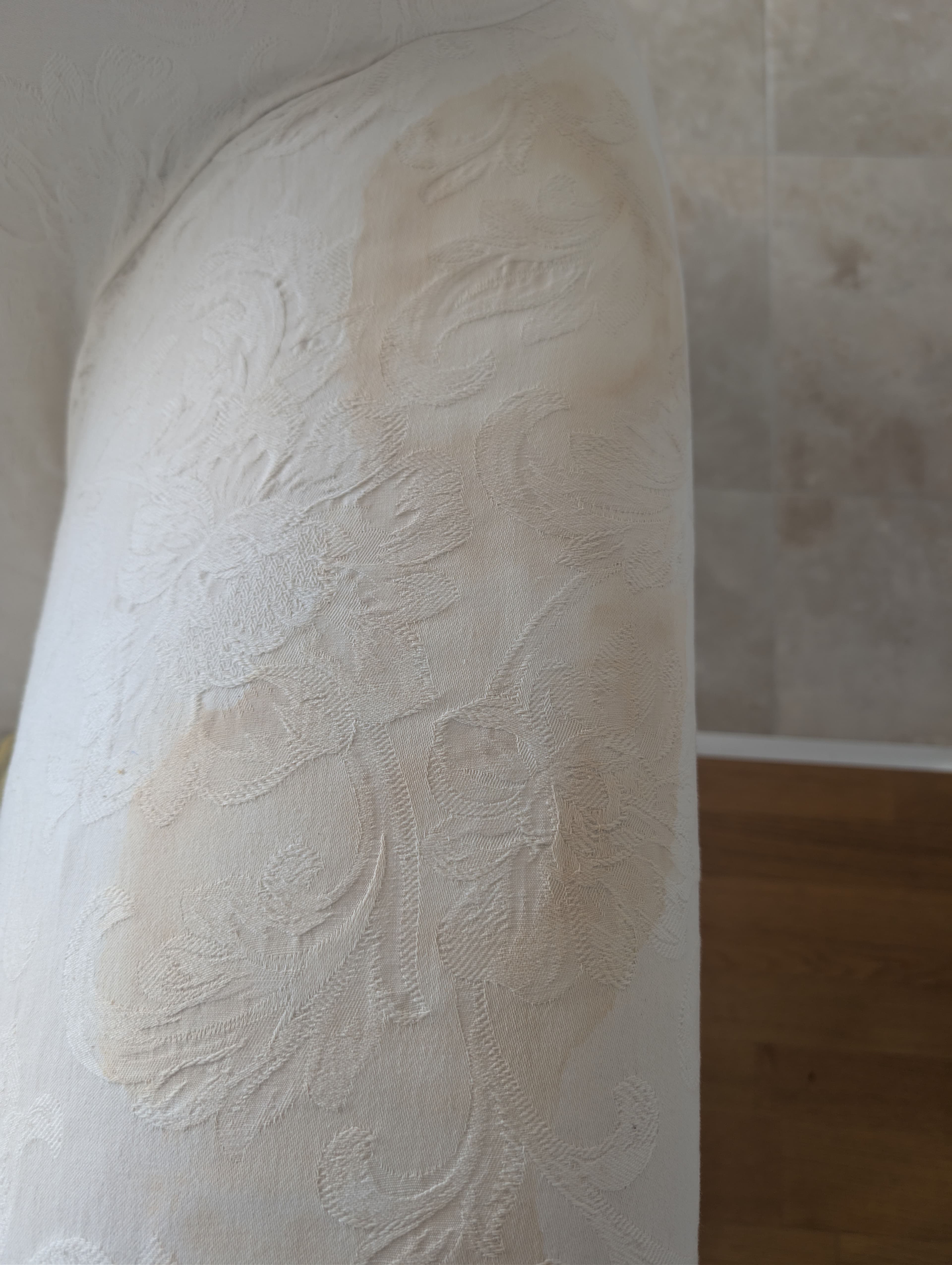 Brown cellulosic-browning stain on the arm of a white cotton sofa before specialist treatment
